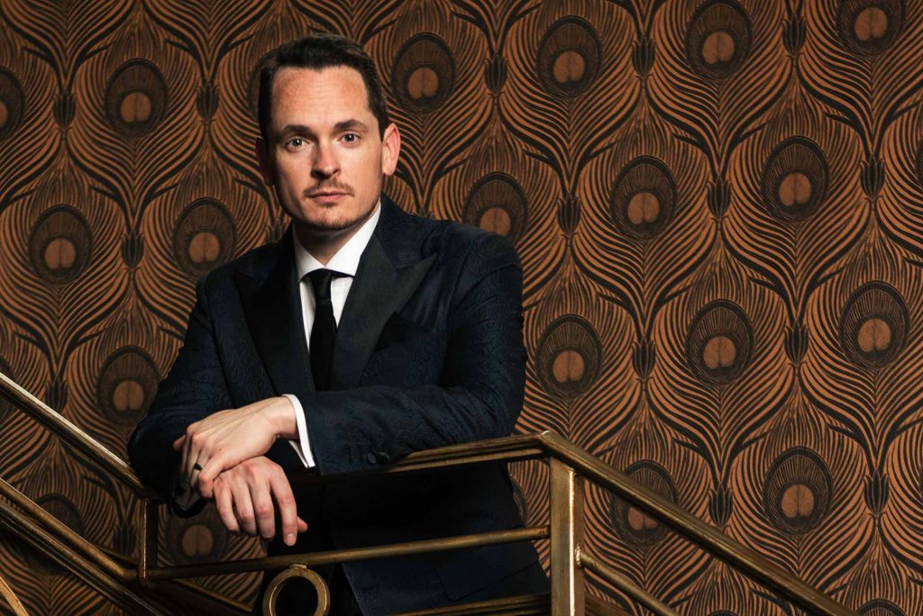 man in a blue custom suit with brown background
